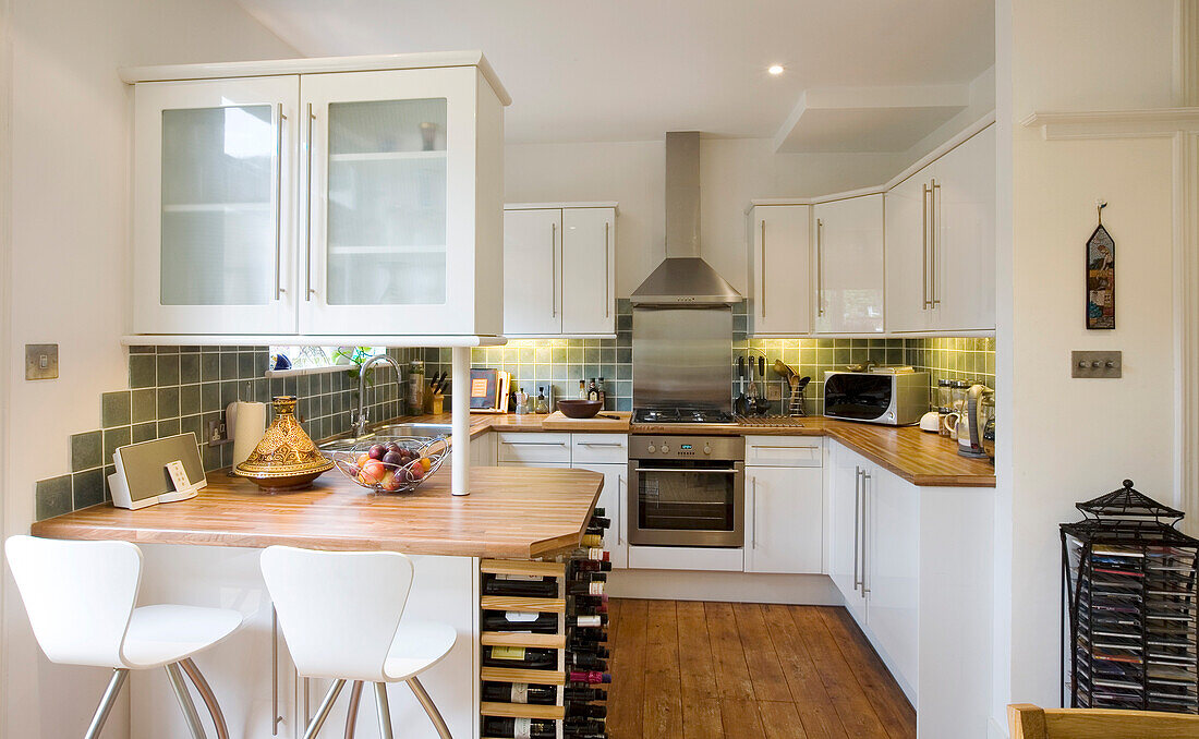 Frühstücksbar mit Weinregal in weißer Einbauküche in einem Haus in New Malden, Surrey, England, UK