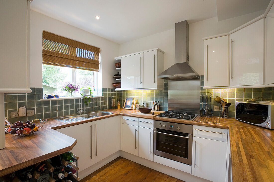 Stainless steel extractor above oven in white fitted kitchen in New Malden home, Surrey, England, UK