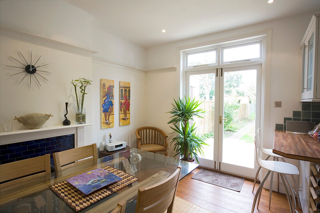 Glass topped dining table with patio doors to garden in New Malden home, Surrey, England, UK