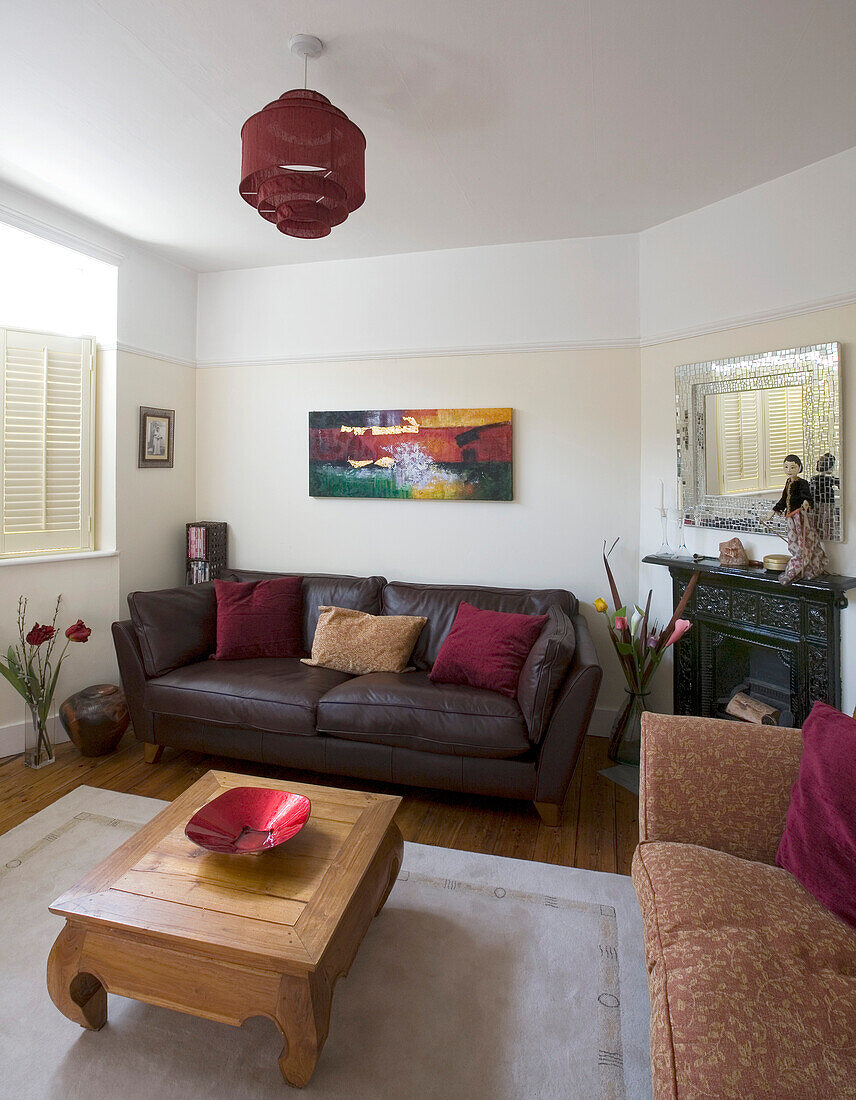 Artwork above brown leather sofa in New Malden home with wooden coffee table, Surrey, England, UK