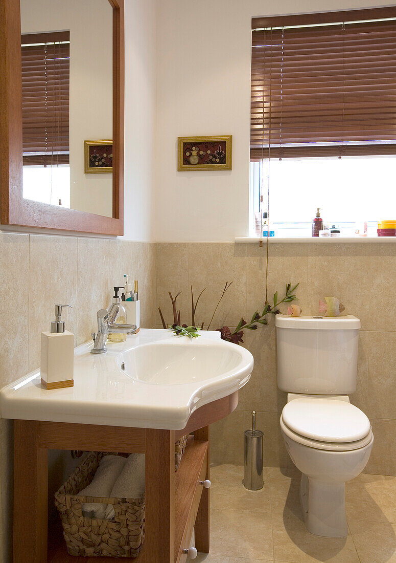 Weißes Keramikwaschbecken und Toilette mit quadratischem Spiegel im Badezimmer eines Hauses in New Malden, Surrey, England, Vereinigtes Königreich