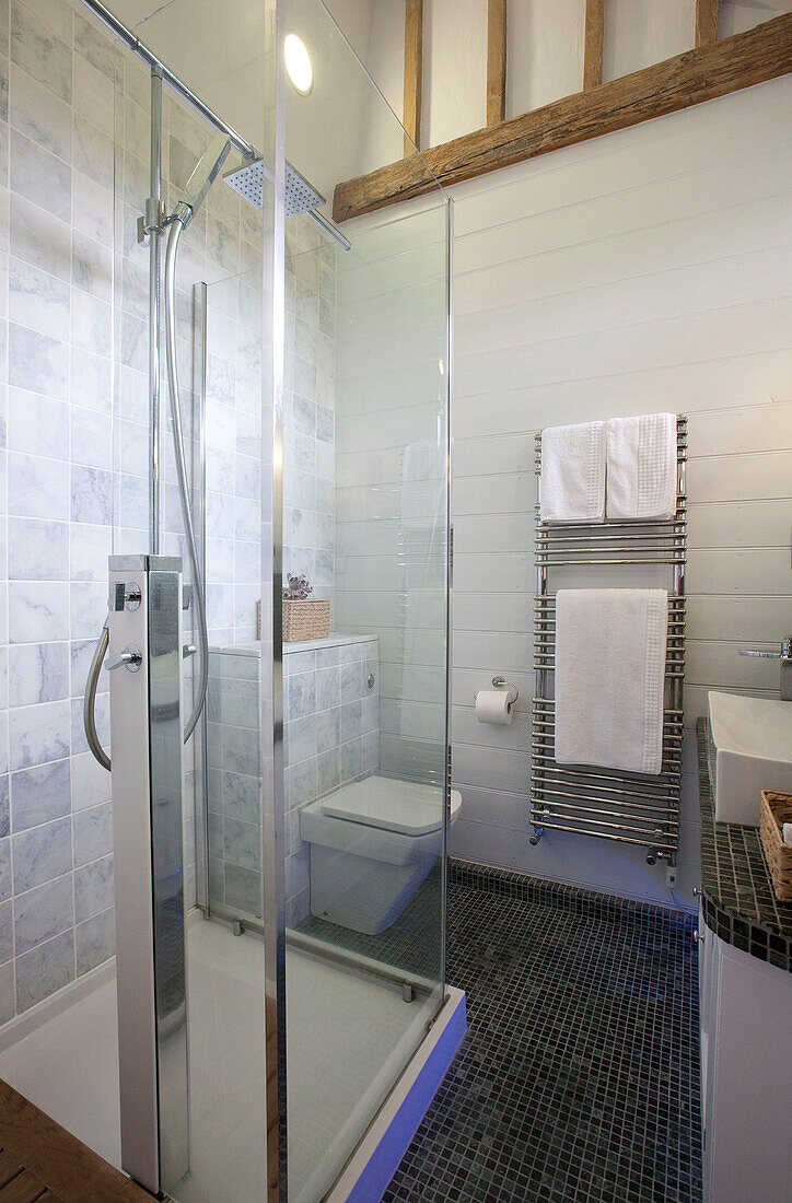 Glass shower cubicle in grey tiled wet room in watermill conversion