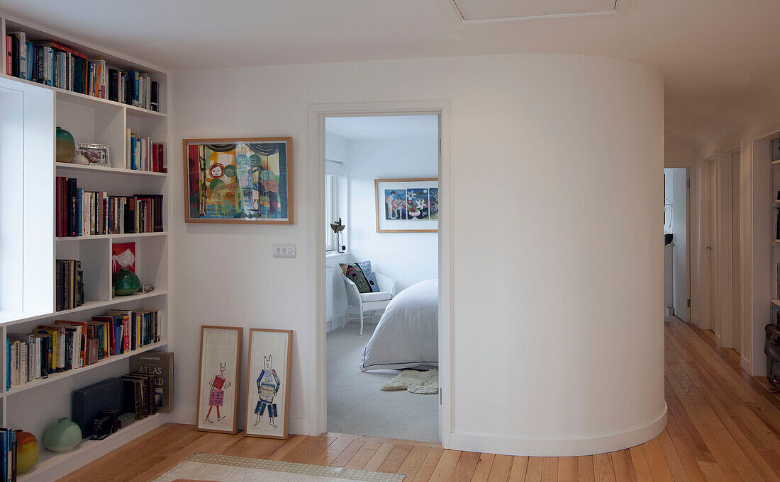 Bookshelf and framed art in hallway with partitioned bedroom in Essex home UK