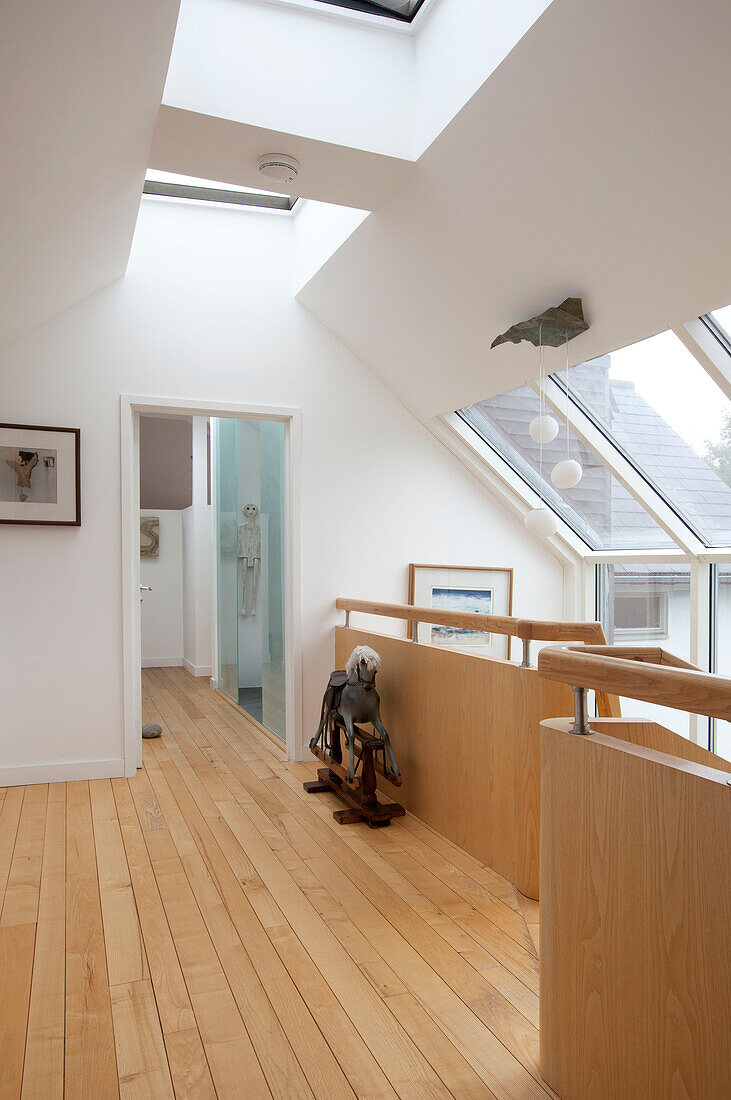 Schaukelpferd auf hölzernem Treppenabsatz mit Dachfenstern in einem Haus in Essex UK