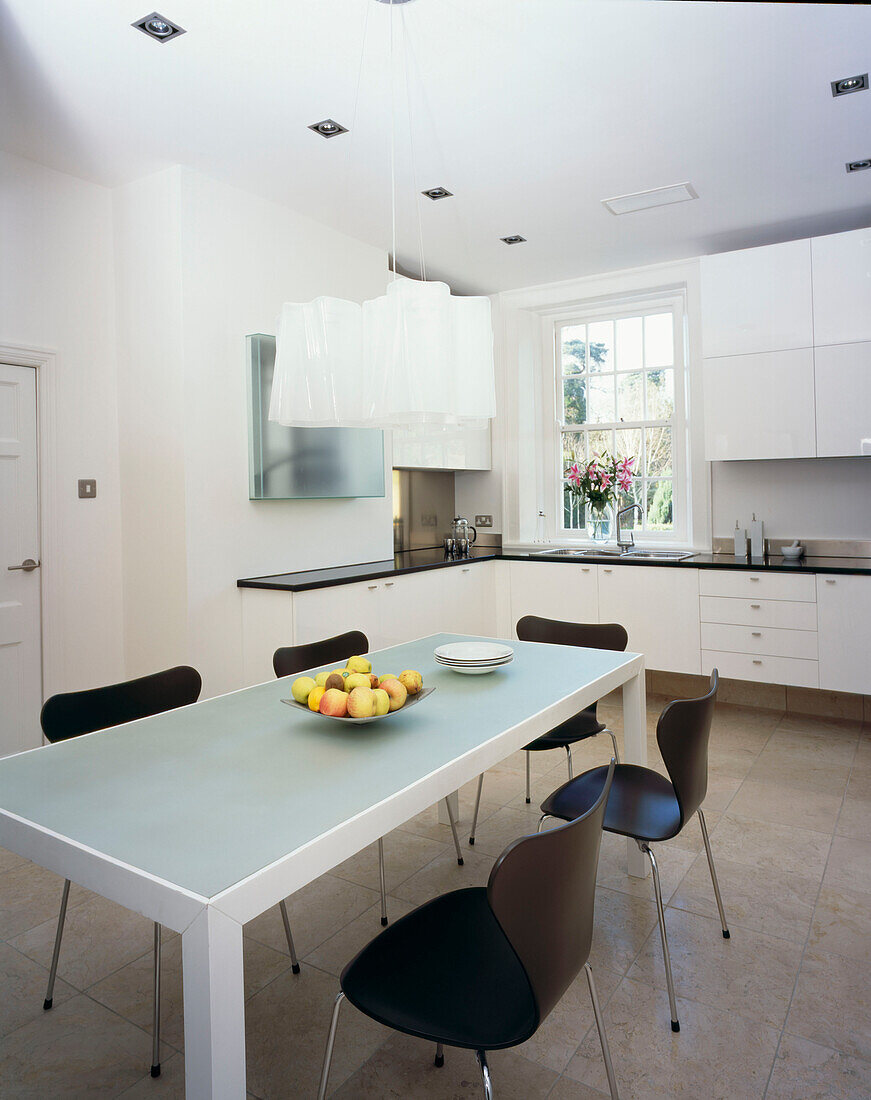 Modern white fitted kitchen diner with frosted glass table