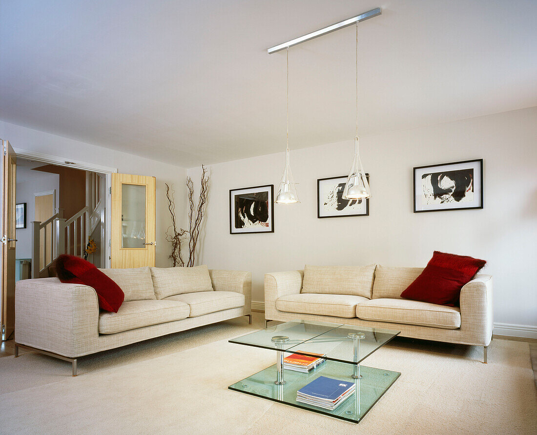 Living room with two cream coloured sofas and glass coffee table