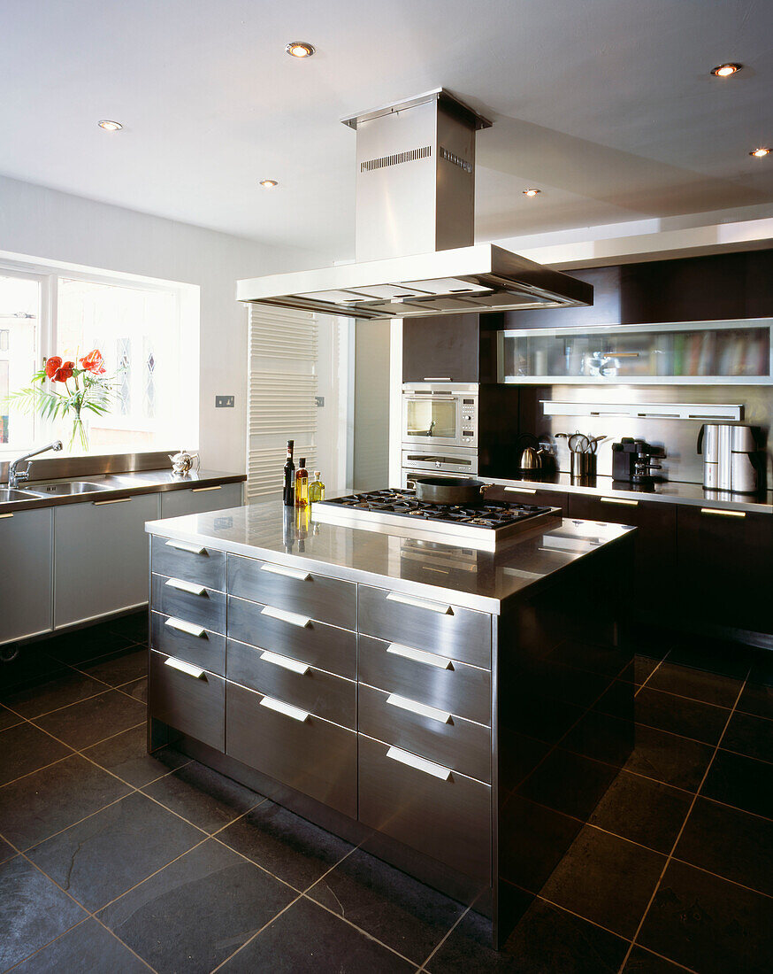Modern fitted kitchen in stainless steel and slate with central island and extractor hood