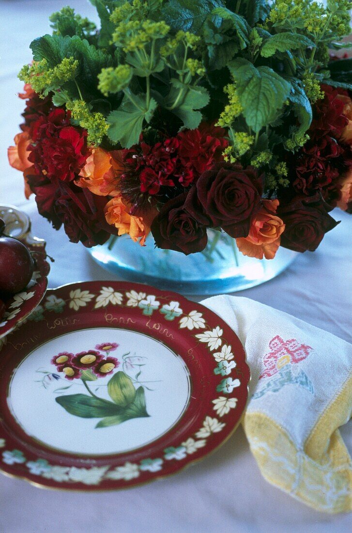 Blumenarrangement mit rotem Blumenteller aus Porzellan