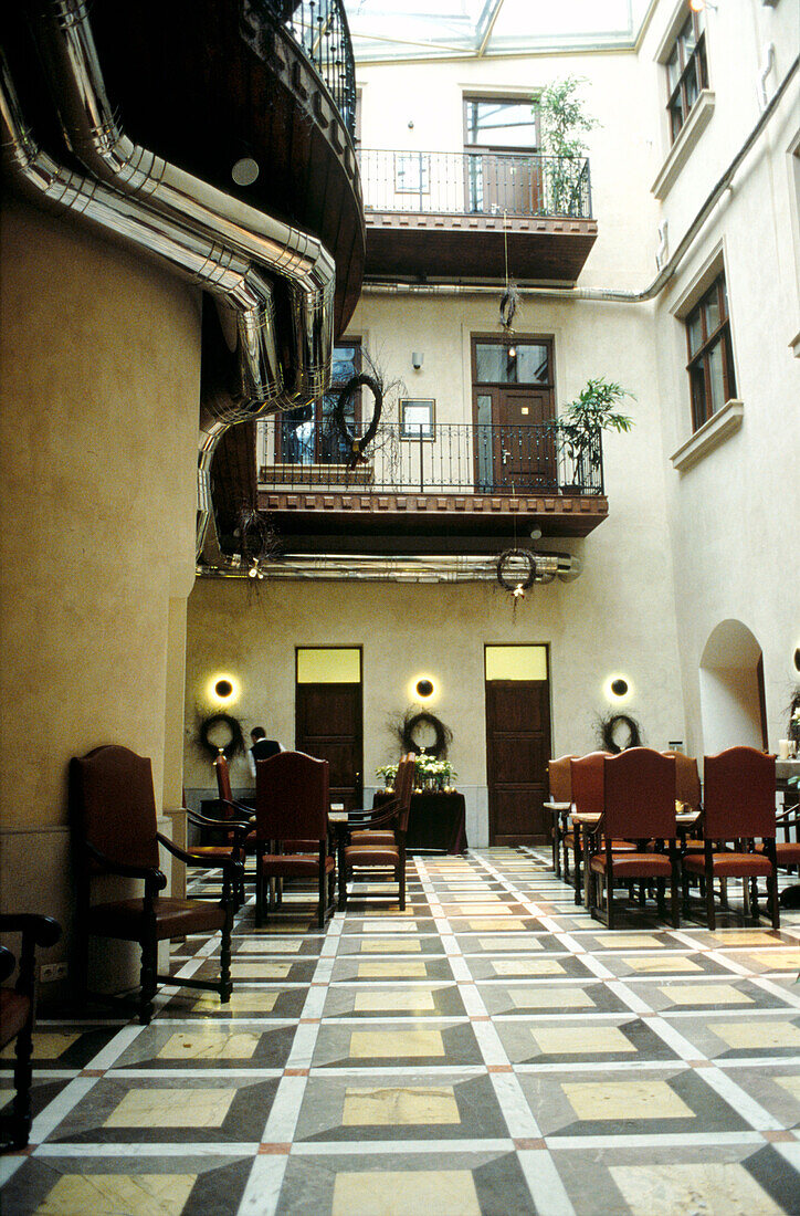 Paved inner courtyard of apartment block with leather dining chairs