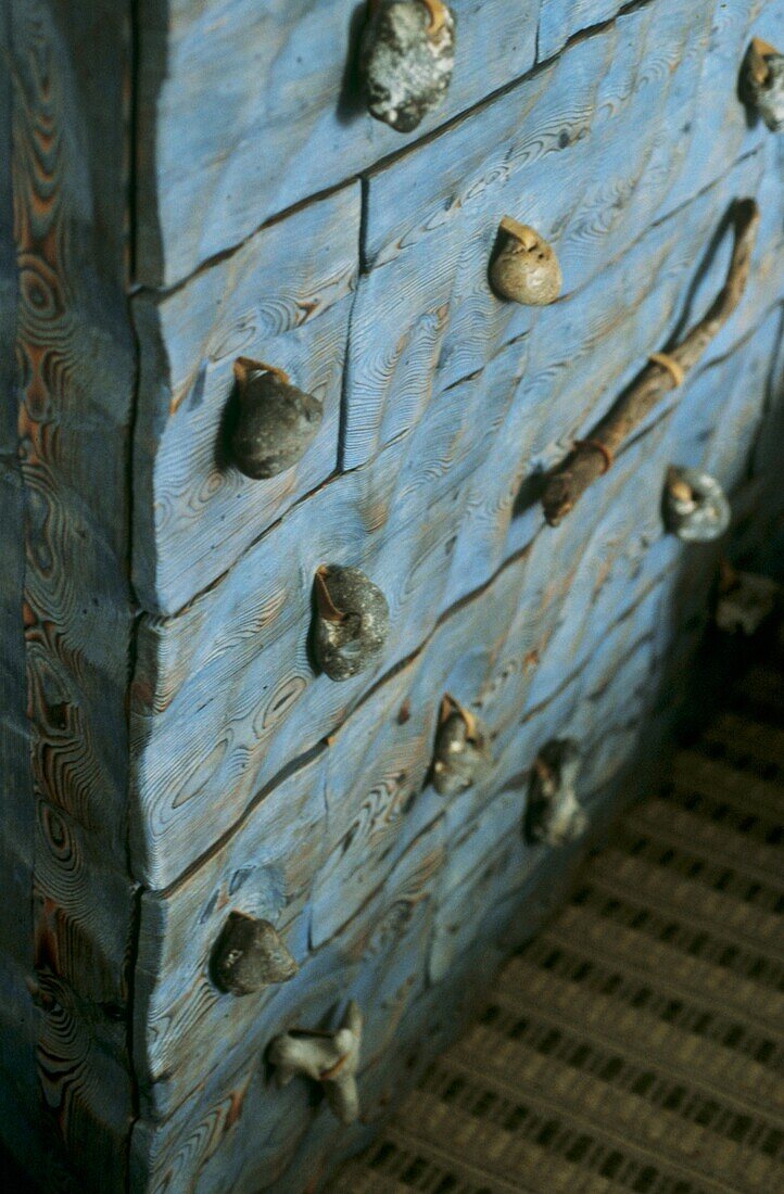 Detail einer blauen verwitterten Holzkommode mit Kieselsteinknöpfen