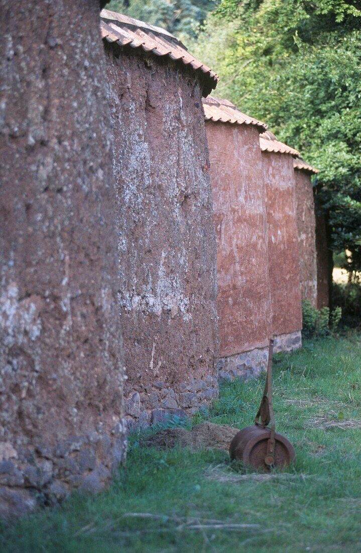 Detail einer geschwungenen Wand mit rostiger Rasenwalze