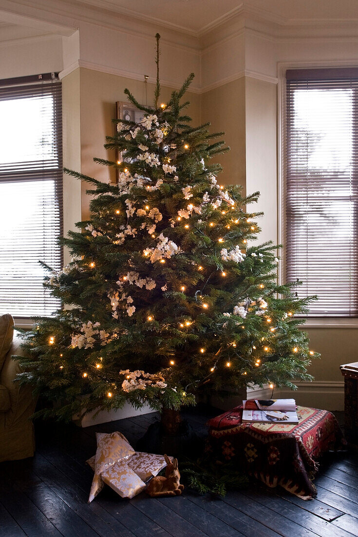 Weihnachtsbaum mit Lichterketten und weißem Blumenschmuck