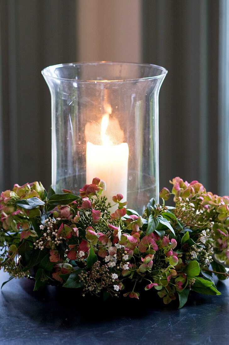 Beleuchtete Kerze mit Blütenkranz