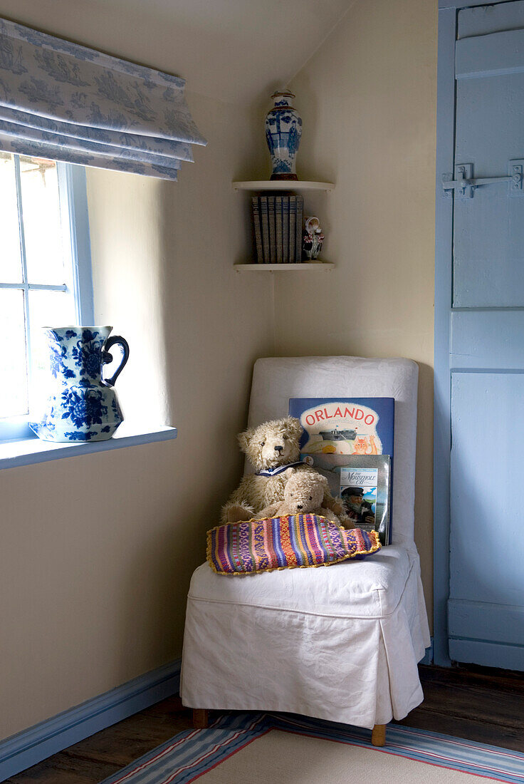 Teddybären auf einem gepolsterten Stuhl in einer Ecke eines Schlafzimmer im Landhausstil