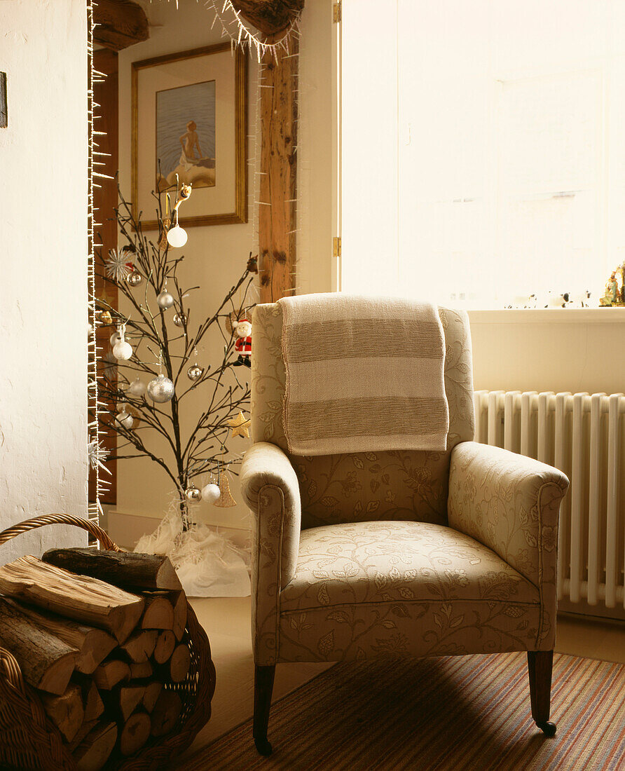 Alter Sessel mit Holzkorb und Weihnachtsbaum mit Kugeln