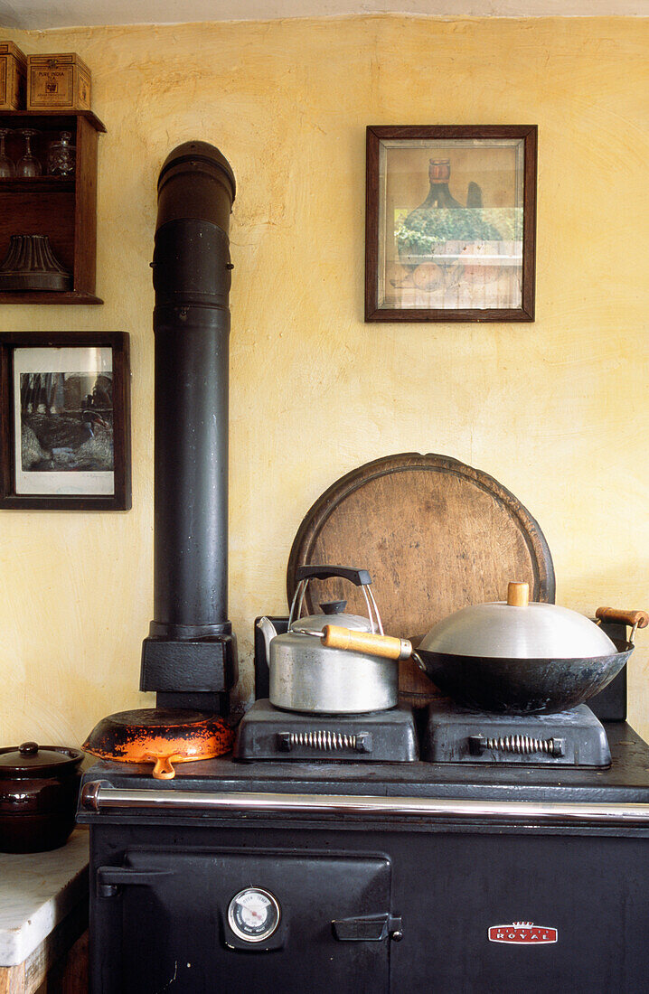 Wasserkocher und Wok auf dem altmodischen Ofen eines edwardianischen Backsteinhäuschens