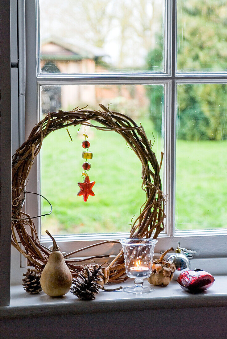 Detail von natürlichen Weihnachtsdekorationen auf einer Fensterbank mit einer Kerze