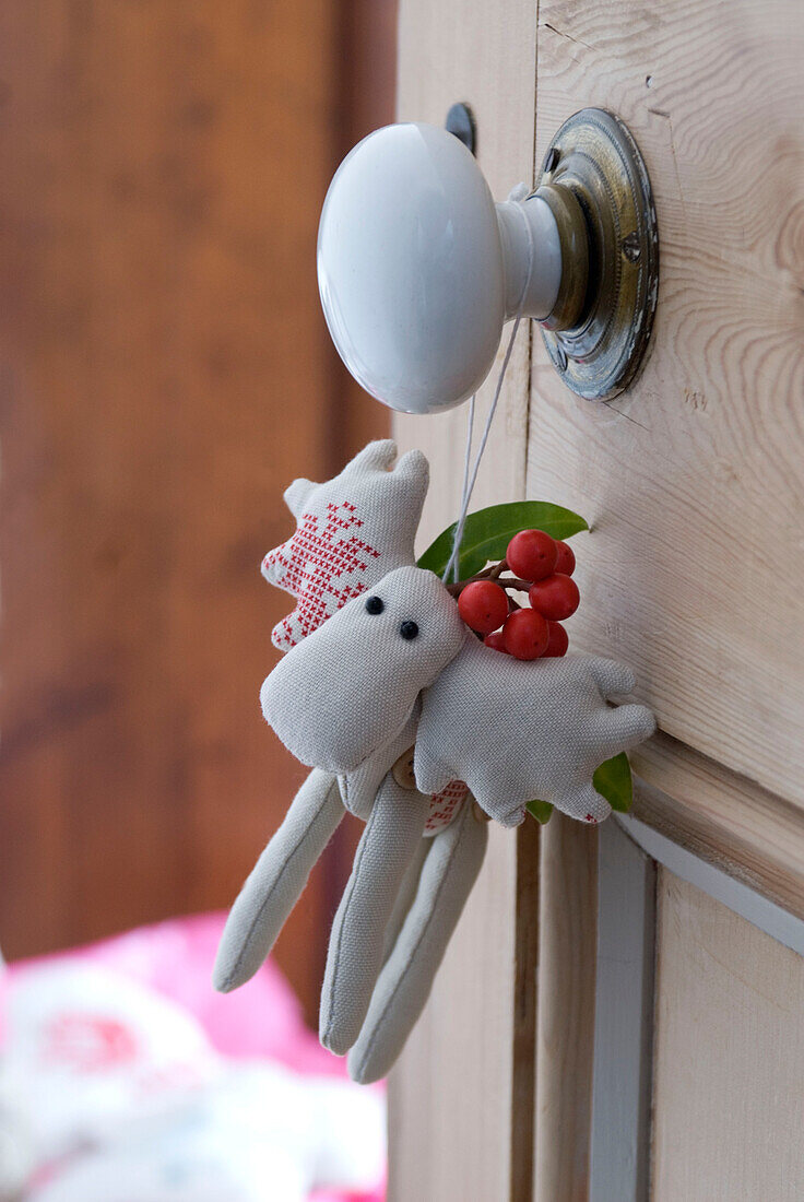 View through stripped pine bedroom door with soft toy christmas reindeer decoration hanging from a porcelain door knob