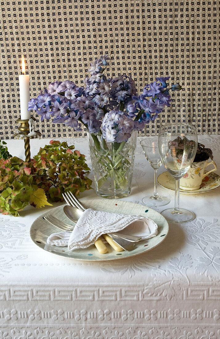 Pretty rustic table setting with candle damask table cloth hydrangeas and hyacinth flowers