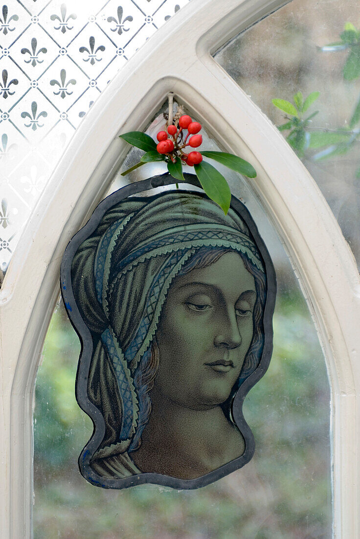 Stained glass decoration of a saint hanging in an arched window