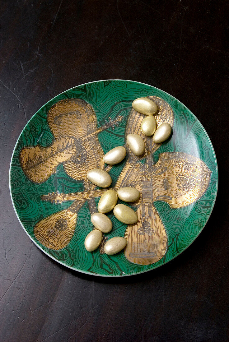 Gold- und grünglänzende Schale mit Saiteninstrumenten verziert und mit Zuckermandeln gefüllt