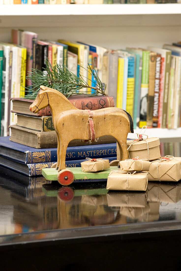 wooden toy horse next to bookcase with small brown paper and string parcels