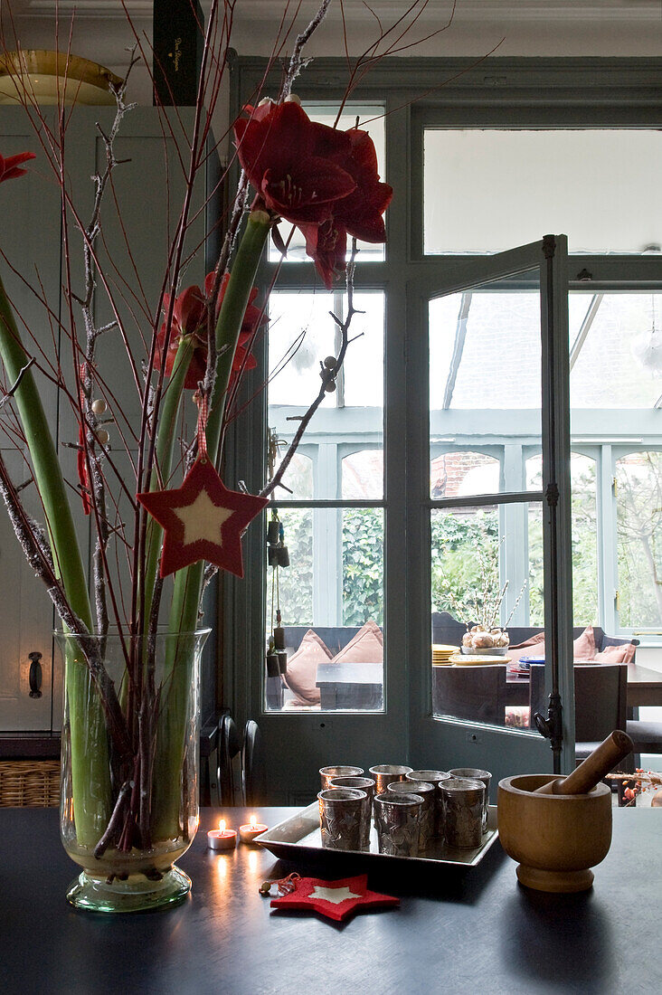 Weihnachtsblumen und sternförmige Dekorationen auf der Arbeitsplatte mit silbernen Bechern und Blick auf die Erweiterung des Esszimmers