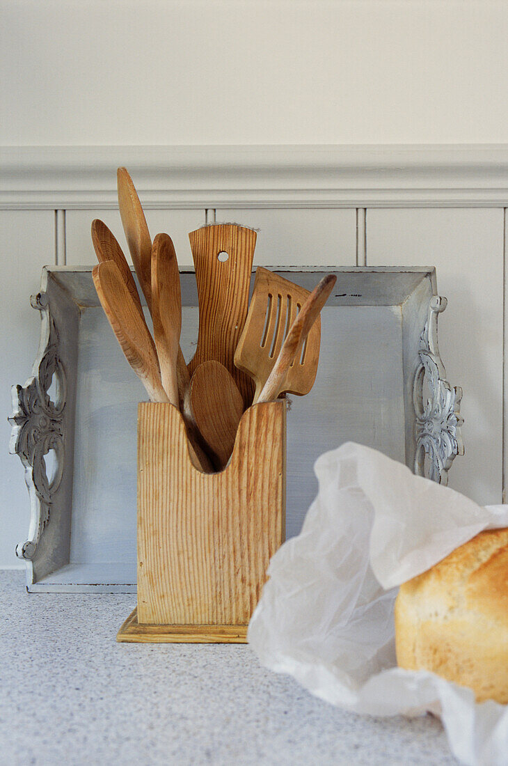 Wooden utensils and a painted grey tray against tongue and groove panelling