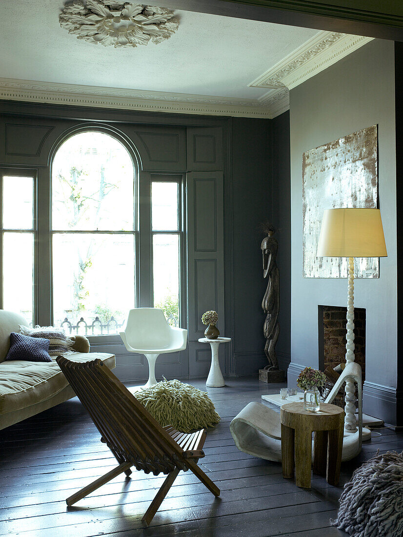 In Grautönen dekoriertes Wohnzimmer mit elegantem Rundbogenfenster mit Fensterläden und einer Mischung aus klassischen und Designermöbeln