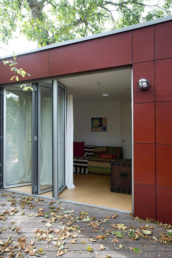 Sliding glass doors on garden extension with autumn leaves on decking