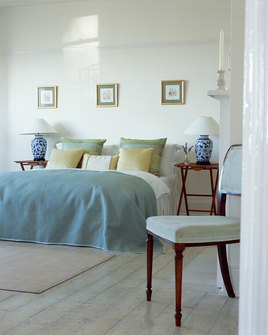 Double bed with matching lamps in bedroom with chair