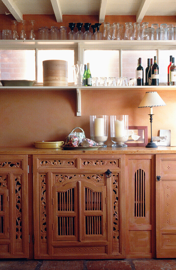 Tableware and candles on carved terracotta kitchen unit