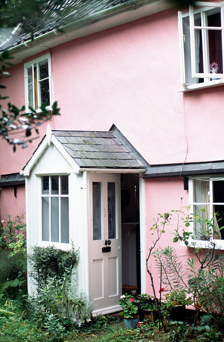 Veranda und Eingangstür eines rosafarbenen Landhauses