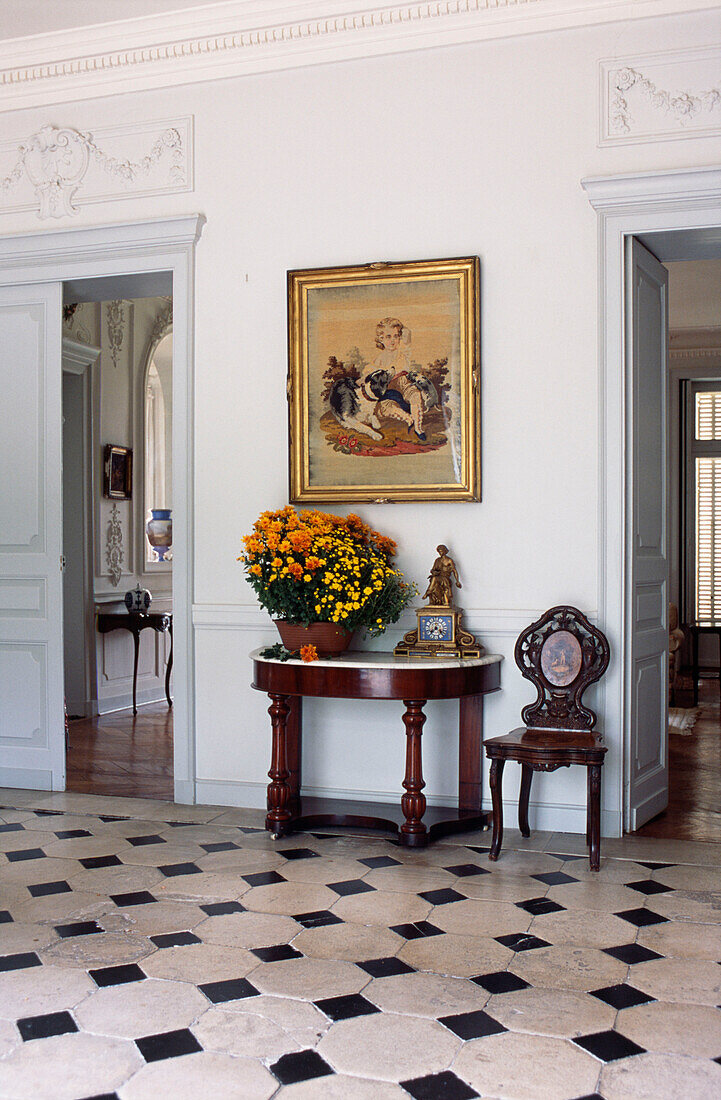 Flower arrangement on demi-lune table in tiled French reception hall