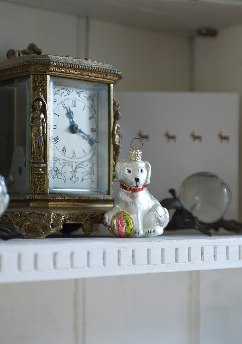 Nahaufnahme einer Kommode mit einer Uhr und Kristalläpfeln aus Wien und einem polnischen Glasbaumschmuck in Form eines Hundes