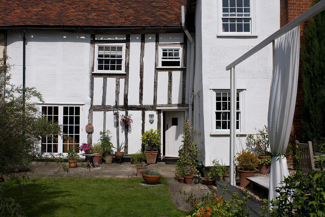 Außenansicht eines historischen Anwesens mit Terrakottatöpfen und Außenvorhang