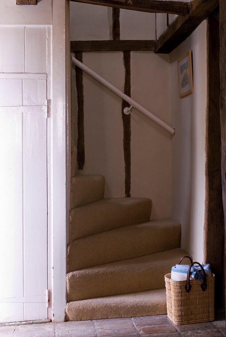 Small staircase with neutral fitted carpet and basket