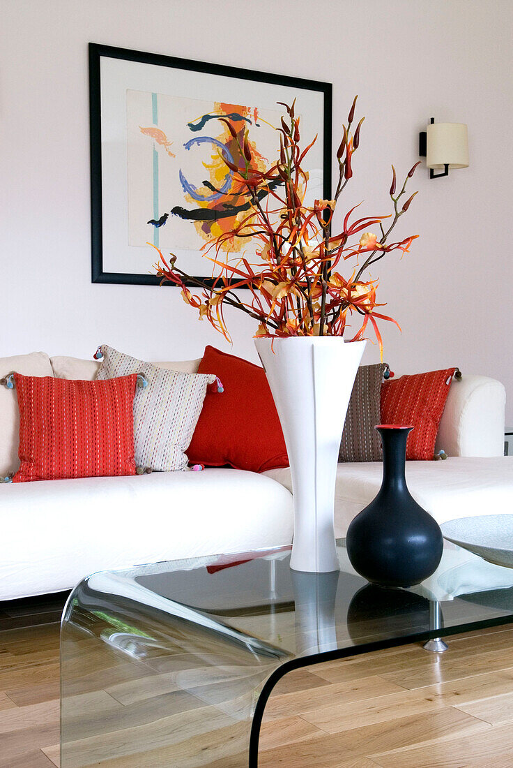 Blumenarrangement und Vase auf Glascouchtisch im modernen Wohnzimmer