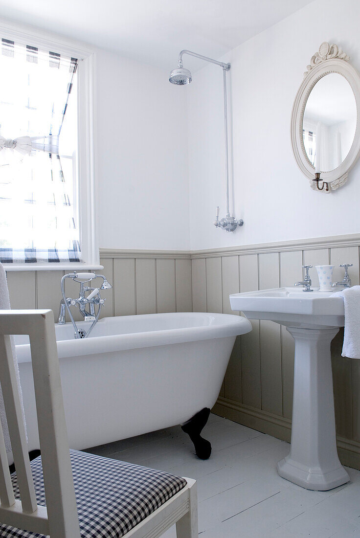Bathroom with moisture-resistant reeded panelling walls voile at the window and free standing claw foot bath 
