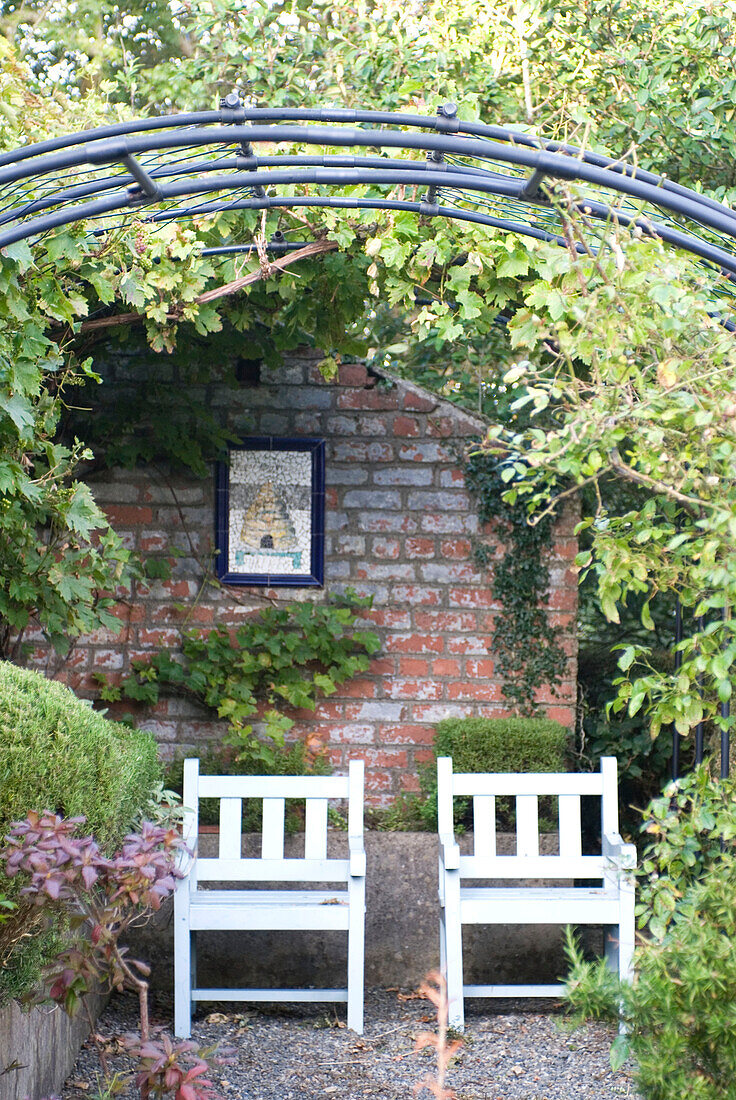 Garden chairs against brick wall under arbor