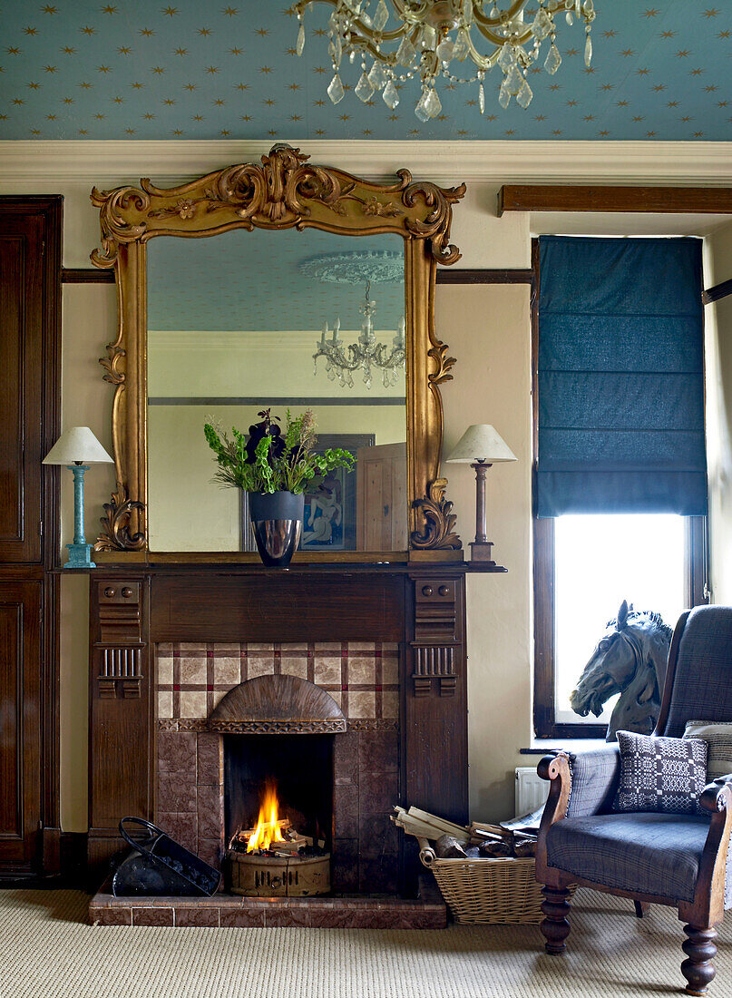 Warme Braun- und Goldtöne und satte Blau- und Grautöne sind die Farben im Wohnzimmer mit blau-goldener Sterntapete an der Decke