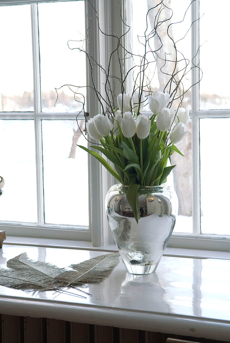 Weiße Tulpen in Glasvase auf Fensterbank