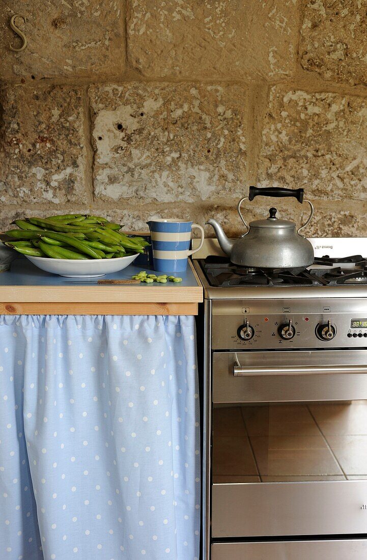 Fresh vegetables beside kettle on kitchen oven