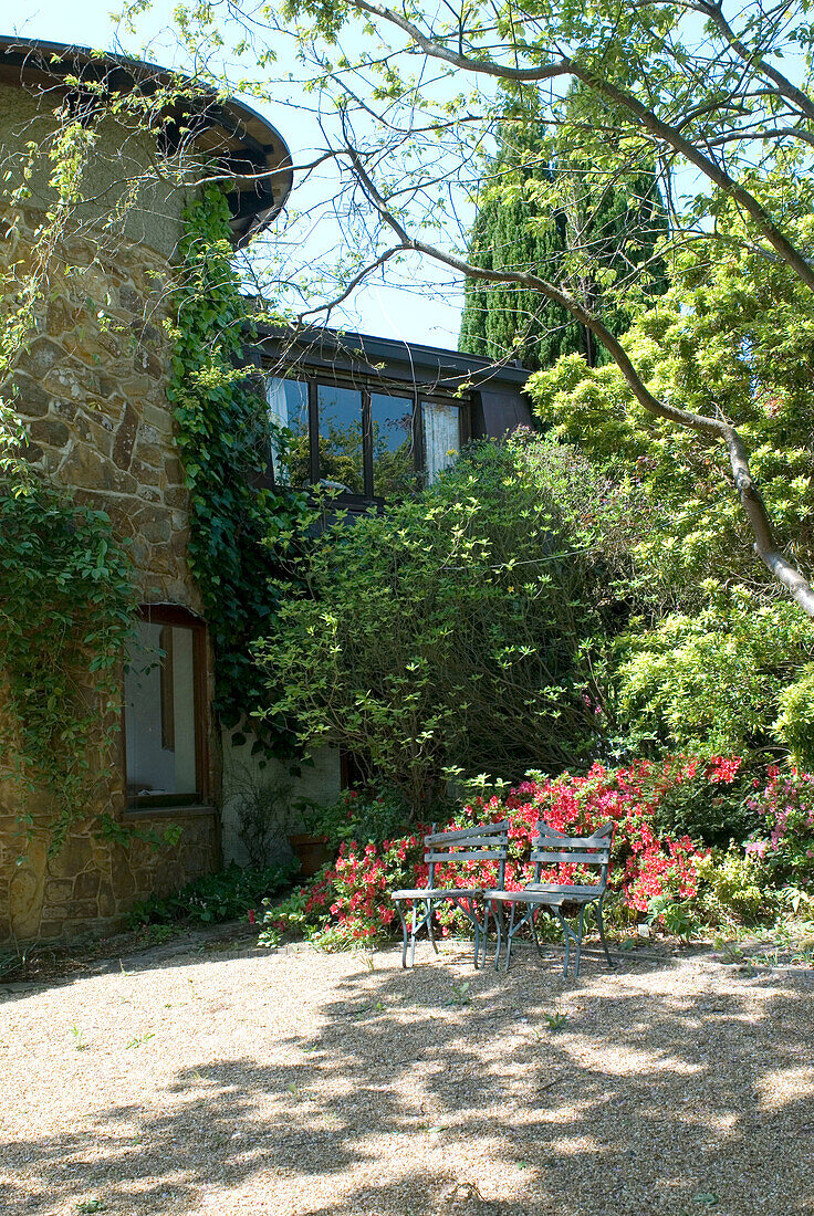Zwei Bänke in einem Garten mit glatten Steinen in der Nähe eines modernen Hauses