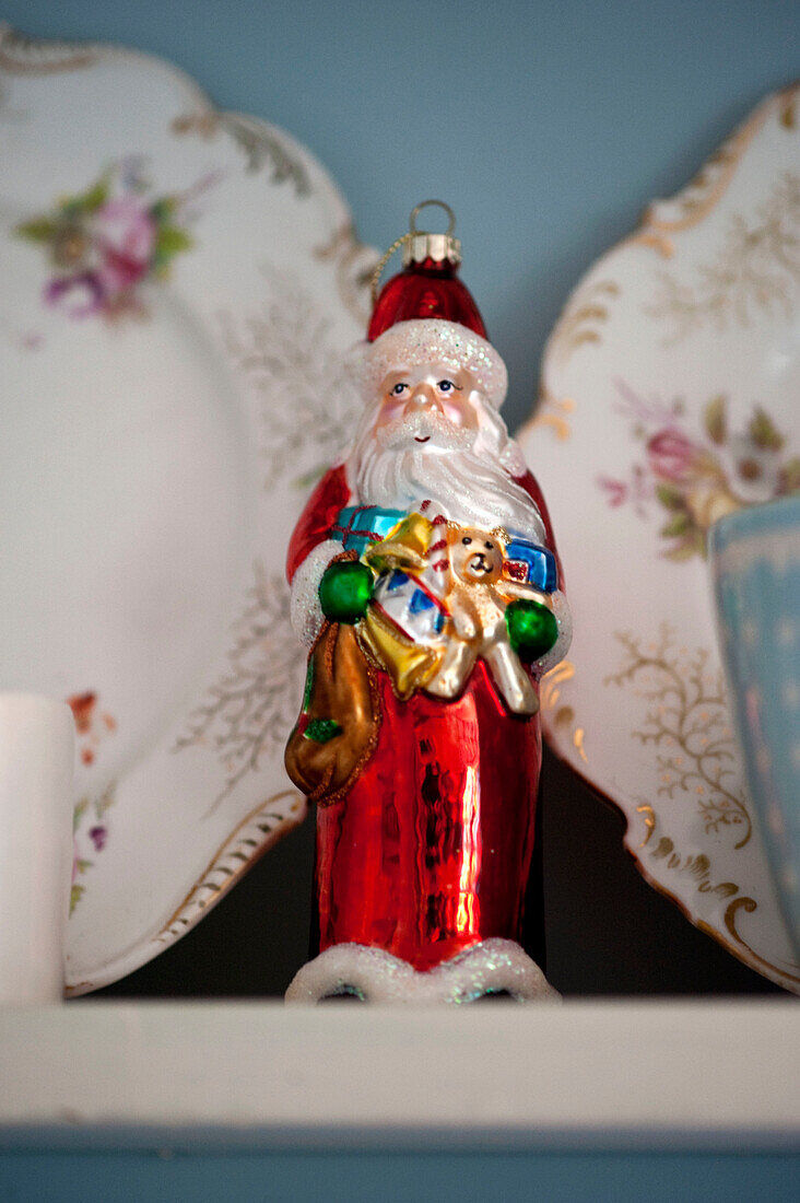 Father Christmas tree ornament and china plates on shelf