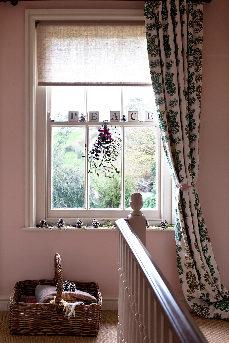 Vorhänge mit Blättermotiv und Raffhalter am Fenster in einem rosafarbenen Hausflur