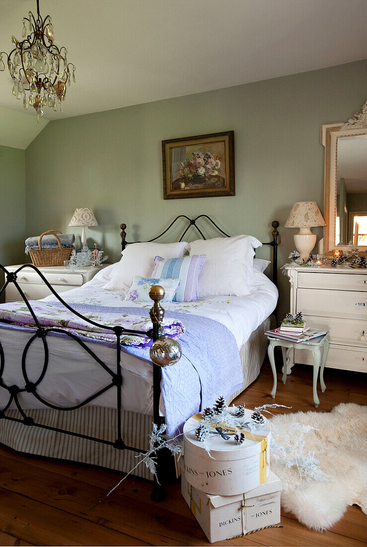 Bett mit Metallrahmen und Hutschachteln in grünem, pastellfarbenem Zimmer