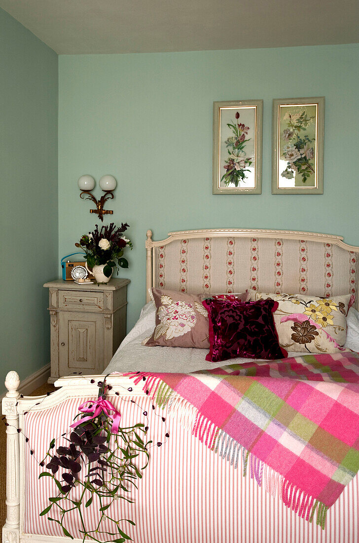 Pink checked blanket on bed with mistletoe and mirrored floral artwork