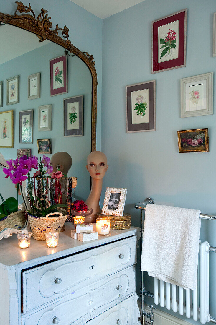 Lit candles and artwork on painted chest of drawers with mirror