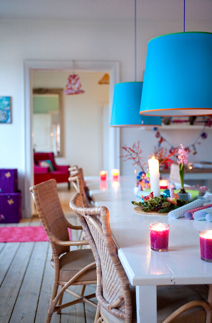Blaue Pendelleuchten hängen über einem Esstisch mit Rohrstühlen in Odense